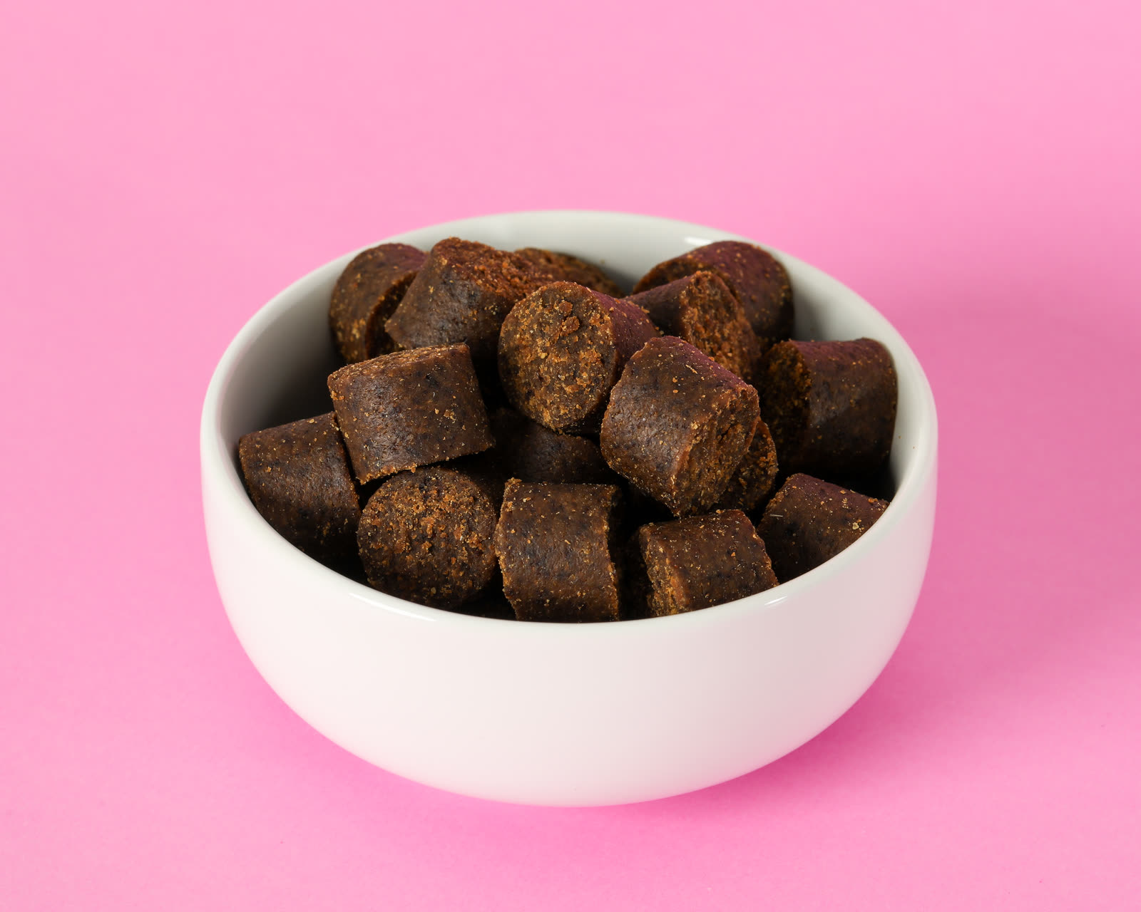 Skin and Coat Soft Chews in a white bowl on a pink background